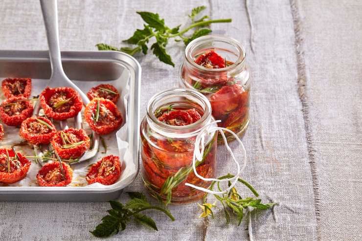 Recept za pripravo posušenega paradižnika. Sestavine za 2 kozarca (1 približno 250 ml):2000 g paradižnika, sol po okusu, 2 žlički sladkorja,olivno olje za kapljanje, 2 vejici svežega rožmarina ali timijana, 300 ml sončničnega olja.